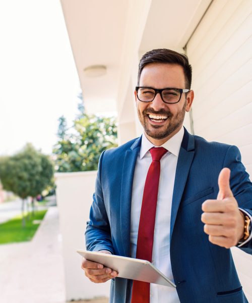Handsome young smiling salesman giving thumbs up