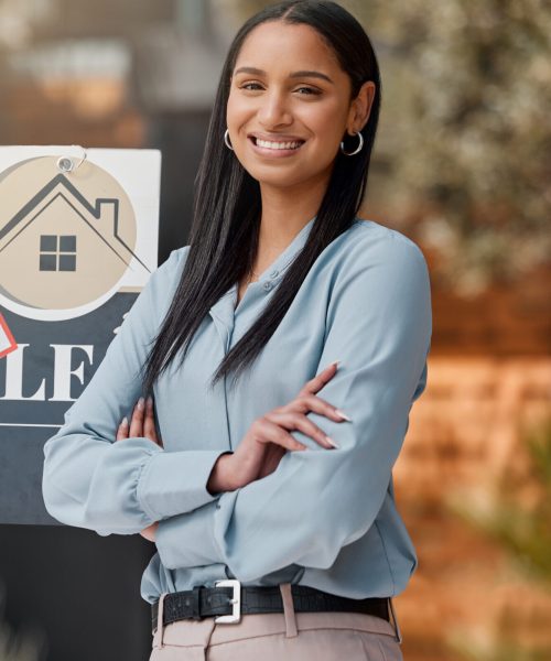 Shot of a real estate agent standing next to a sold sign outside.